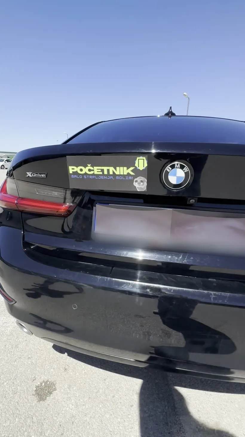 Magnetna tabla „Početnik, malo strpljenja, molim!” na poklopcu gepeka crnog BMW-a