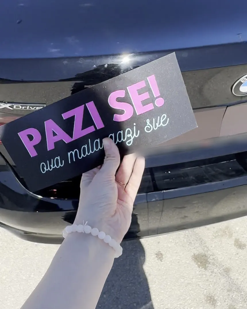 Ruka prislanja magnetnu tablu „Pazi se! ova mala gazi sve” na poklopac gepeka